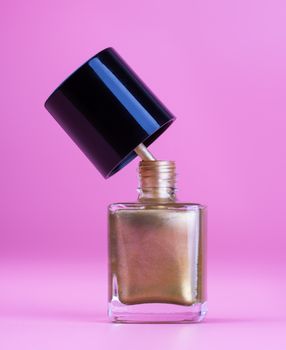 Nice bottle of gold nail polish, pink background