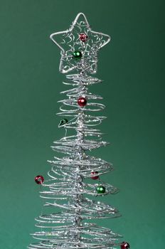 Silver Christmas tree with ornaments. Green Background