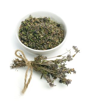 Dried thyme in a bowl and thyme twigs on white background