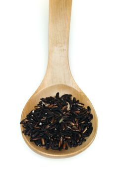 Black rice in wooden spoon on white background.