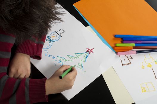 Boy drawing with markers. Multicolored papers