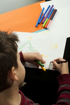 Boy drawing with markers. Multicolored papers