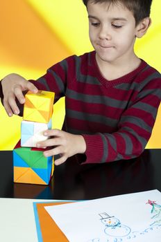 Little boy playing with multicolored cubes.