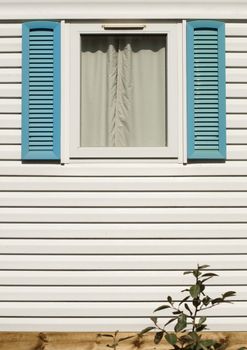 Window with blue wooden shutters. White wall