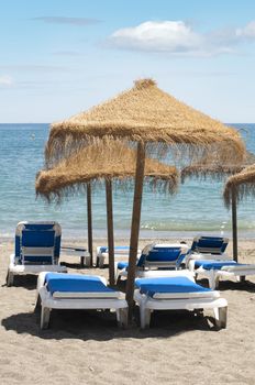 Straw beach umbrellas and sunbeds on the beach