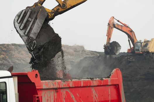 Excavator loading truck. White isolated