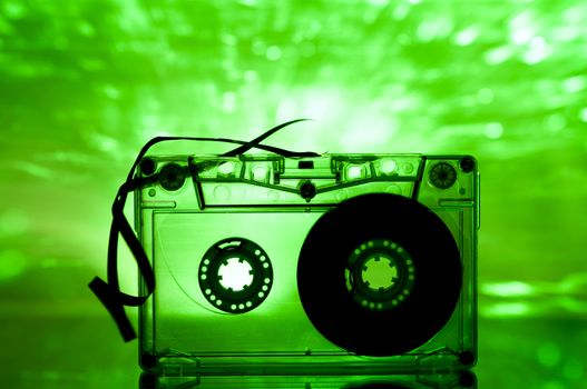 Cassette tape and multicolored green lights on background