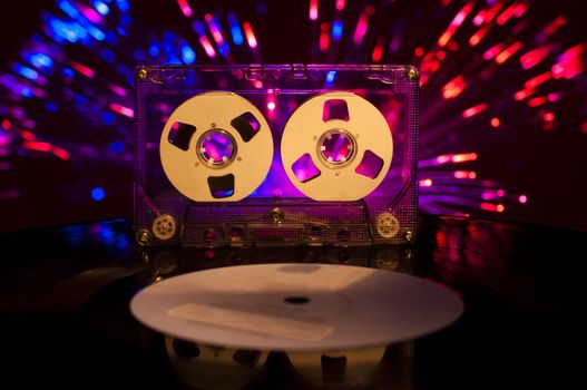 LP vinyl record, cassette tape and disco lights on background