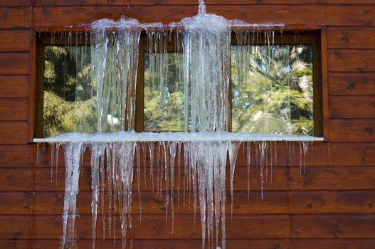 Icicles on window. Wooden house windows