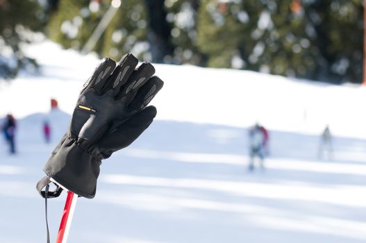 Ski gloves and sticks. Winter tourists on the background.