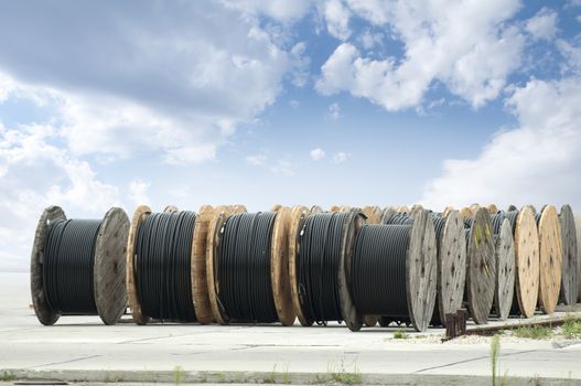 Large rolls of black cables on blue sky background