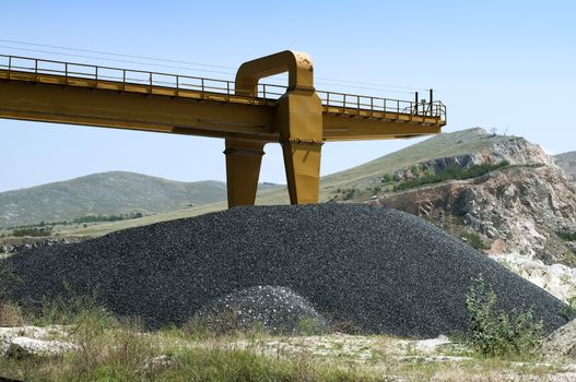 Balck asphalt pile and crane in quarry