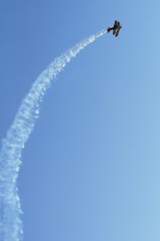 Red plane looping in a blue sky. Vertical image