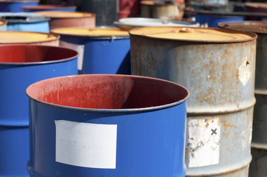 Old colored barrels for oil products. Empty rusted drums