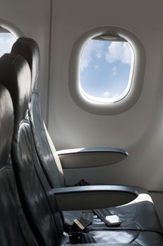 Inside an empty plane. Window and blue cloudy sky