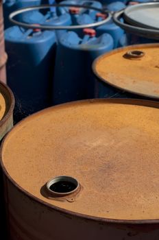 Old colored barrels for oil products. Empty rusted drums and blue canisters