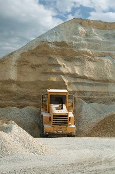 Bulldozer in quarry. Huge pile of limestone and sand
