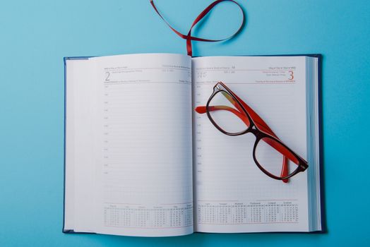 Business planning with copy space and office supplies. Red glasses on blue background
