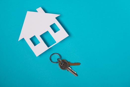 Silver key with house figure on blue background. Top view.