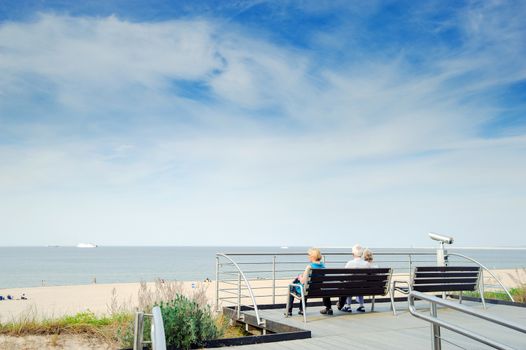 tourists sit on a bench at the beach