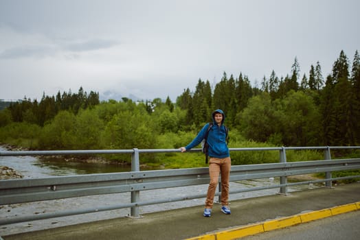 male tourist standing beside the mountain river.