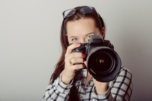 Woman-photographer takes images, isolated on gray background