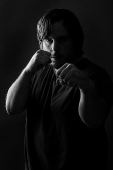 Low key photo of a heavy set guy getting ready to fight.
