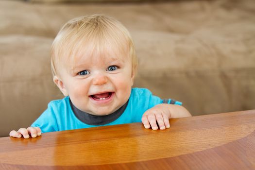 Toddler trying to hold himself up nice and proud at the edge of the table