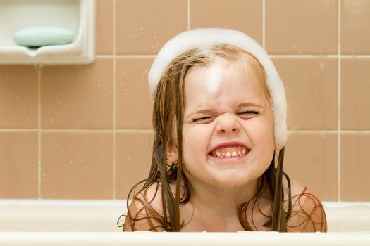 Playing in the tub making a weird funny face or smile, this cute girl is having fun.