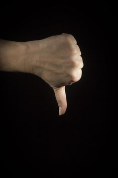 Female hand showing a thumb down gesture. On a black background