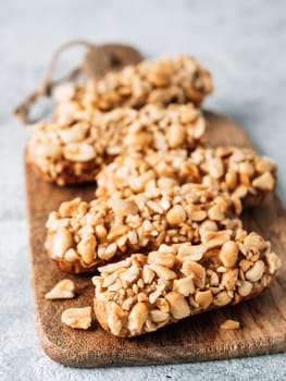 Homemade eclairs with peanut on cutting board. Close up view of delicious healthy profitroles with nuts. Copy space for text or design. Vertical.