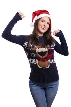 Beautiful young smiling girl wearing a Christmas hat and sweater, raising her hands in celebration, isolated on white background. Christmas and New Year concept.