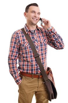 Communication concept. Portrait of a handsome smiling casual man in plaid shirt and a shoulder bag talking on mobile phone, isolated on a white background.