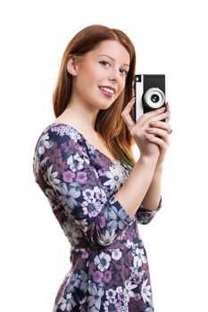 Side portrait of a fashinable, beautiful smiling young girl taking a photo with an old film vintage camera, isolated on white background.