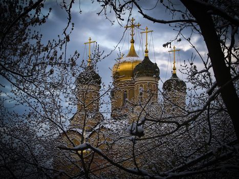 Winter city in the snow. The Church with Golden crosses is surrounded by snow-covered trees.