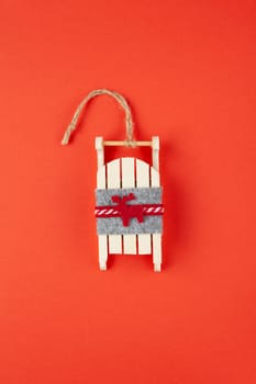 Christmas decoration, tree toy, wooden sled with deer on red background, for social media. Festive, New Year concept. Vertical, flat lay. Minimal style. Top view.