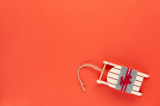 Christmas decoration, tree toy, wooden sled with deer on red background with copy space. Festive, New Year concept. Horizontal, flat lay. Minimal style. Top view.