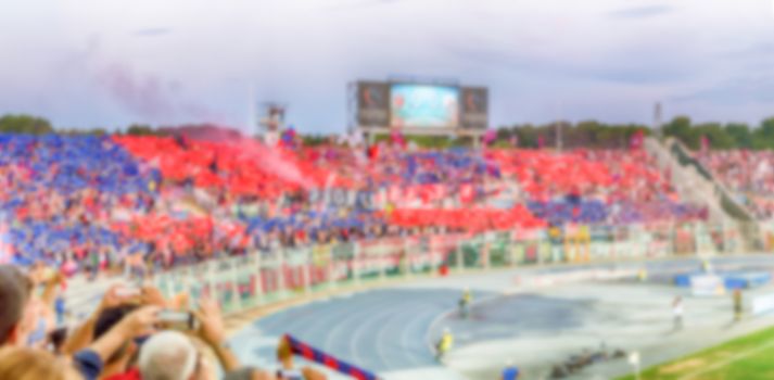Defocused background with supporters in the stadium for football match. Intentionally blurred post production for bokeh effect
