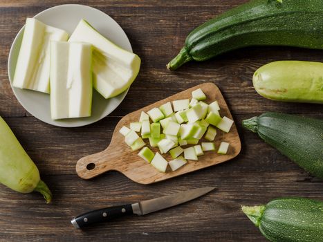 Zucchini harvest. Slices farm organic zucchini cubes for freezing on woodencutting board over brown wooden table. Zucchini harvesting concept. Top view or flat lay.