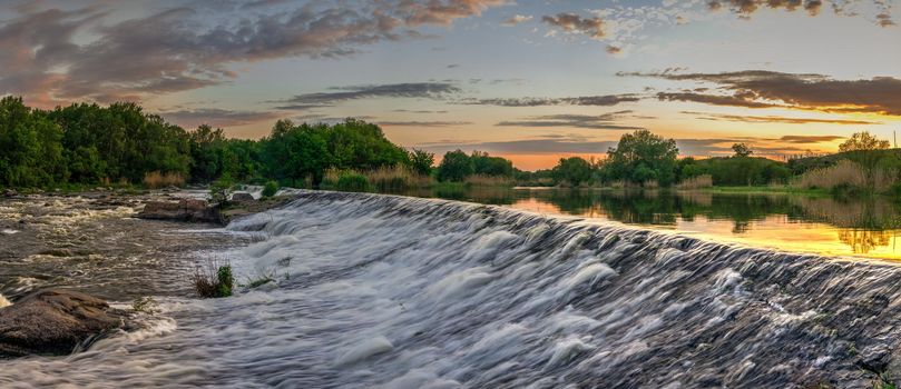 Beautiful view of the dam on the Southern Bug River at sunset. Village of Migiya, Ukraine, on a sunny summer evening