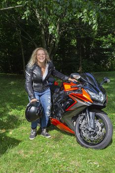 twenty something blond woman, standing beside her sport motocycle, laughing her heart out