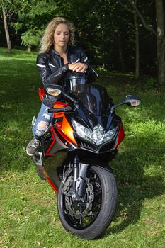 Young blond woman, sitting on a sport motocycle, with her eye closes and meditating