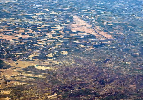 Top view of the ground from the plane. European landscape. Colorful pattern of trees, fields, rivers and lakes. Soft focus.