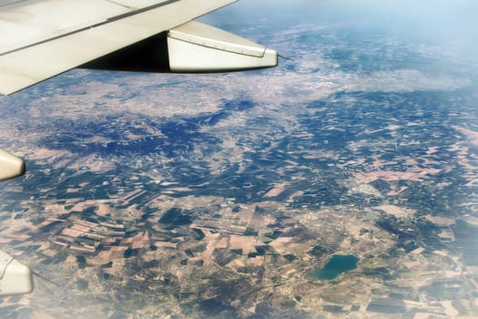 Top view of the ground from the plane. European landscape. Colorful pattern of trees, fields, rivers and lakes. Soft focus.