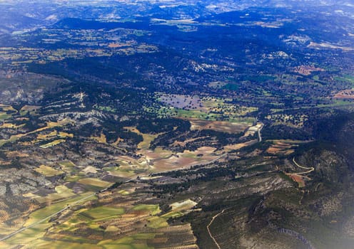 Top view of the ground from the plane. European landscape. Colorful pattern of trees, fields, rivers and lakes. Soft focus.