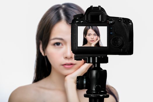 Asian American beauty vlogger creating content for social media vlog, behind camera shot