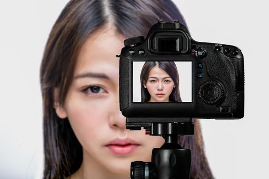 Asian American beauty vlogger creating content for social media vlog, behind camera shot