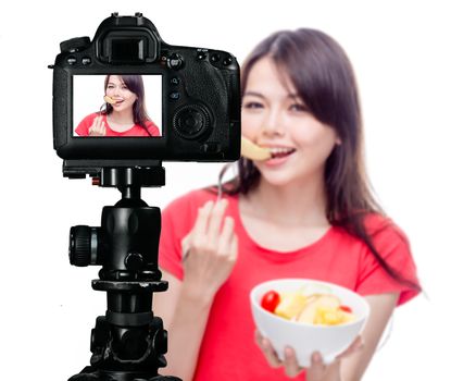 Asian food vlogger with fruit salad behind camera, social media production concept