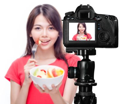 Asian food vlogger with fruit salad behind camera, social media production concept