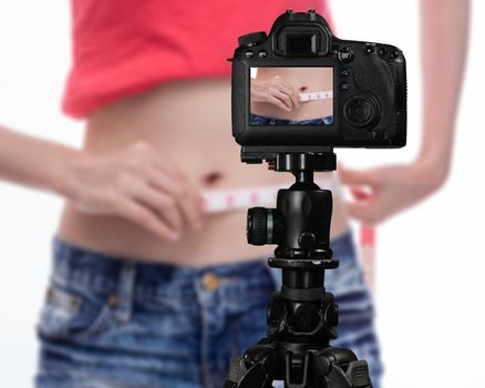 Asian vlogger measuring waist behind camera, social media production concept